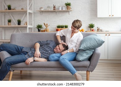 Happy Dreamy Young Caucasian Couple Relaxing On The Sofa In The Designer Living Room, Relaxing Hugging