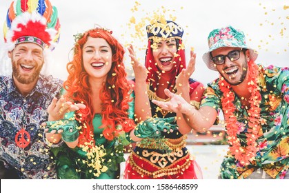 Happy dressed people celebrating at carnival party throwing confetti - Young friends having fun together at fest event - Youth, hangout, festive and happiness concept - Focus on left couple hands