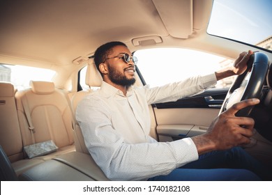 Happy Driver. African Man Driving Own New Car Sitting In Seat And Smiling. Selective Focus