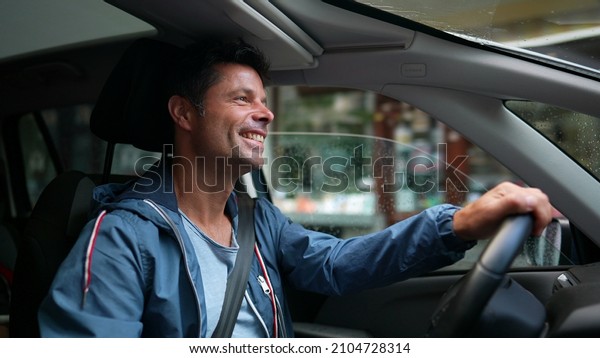 Happy\
driver holding steering wheel driving in\
city