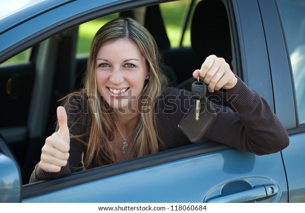 A happy driver leaning out of the window and showing\
the car key