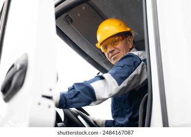 Happy driver man of industrial dump truck sits in cab and works on construction building site - Powered by Shutterstock