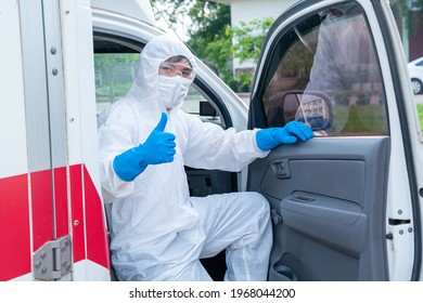 Happy Driver Wear PPE In Front Of The Ambulance With Protective Suit, Mask Gloves At Ambulance Car Vehicle For Helping The Patient Of Coronavirus Or Covid-19 