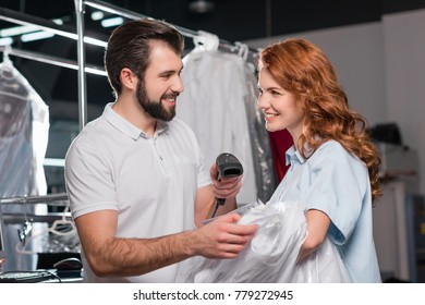 Happy Dry Cleaning Workers Scanning Barcode On Bag With Shirt