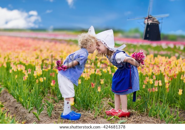 花の咲くチューリップ花畑で遊ぶオランダの幸せな子どもたち オランダのオランダのホランドで 伝統的な民族衣装 木の下駄 帽子を着て風車の横にチューリップで遊ぶ少年少女 の写真素材 今すぐ編集