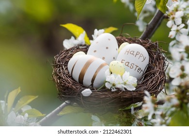 Happy Easter 2022. A postcard with a copy of the place for the text. White and golden eggs in a bird's nest on a natural background of cherry blossoms. - Powered by Shutterstock