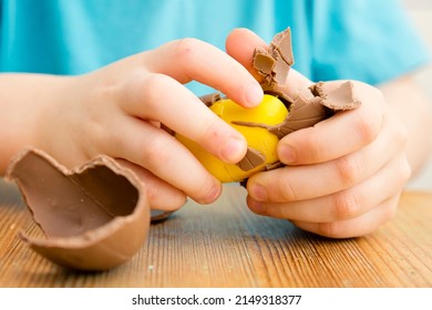 Happy Easter. Close-up of children's hands open breaking chocolate egg with surprise. Happy family vacation.