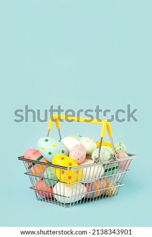 Happy Easter. Colored easter painted eggs in a shopping basket with copy space over blue background