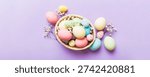 Happy Easter composition. Easter eggs in basket on colored table with gypsophila. Natural dyed colorful eggs background top view with copy space.
