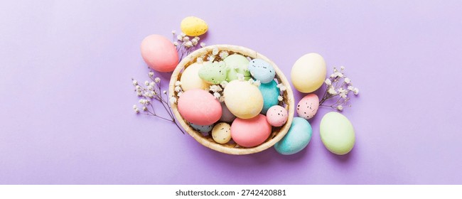 Happy Easter composition. Easter eggs in basket on colored table with gypsophila. Natural dyed colorful eggs background top view with copy space.