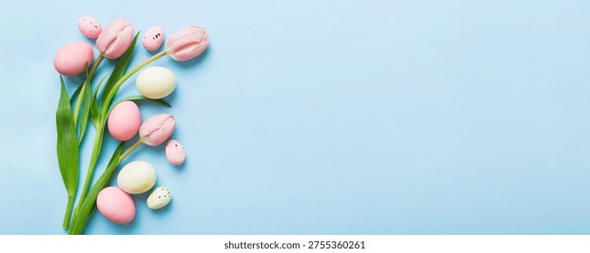 Happy Easter composition. Easter eggs on colored table with yellow Tulips. Natural dyed colorful eggs background top view with copy space.