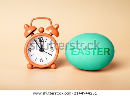 Happy Easter concept. Alarm clock and painted egg. High quality photo