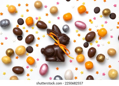 Happy Easter concept. Delicious traditional chocolate Easter bunny, eggs, sweets, almonds, sugar stars on white table background. Preparation for holiday. Simple minimalism flat lay, top view - Shutterstock ID 2250682557