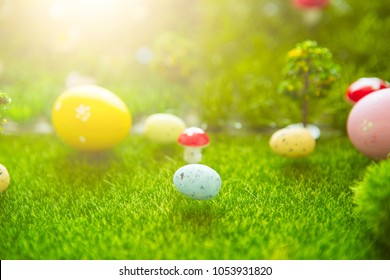 Happy Easter concept. Easter eggs on green grass. Fairy tale sunset on the plastic green field with plastic grass, mushrooms and trees. Fake grass. Macro.