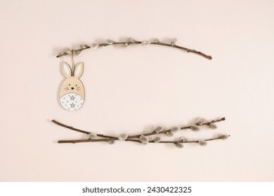 Happy Easter concept. Flat lay, top view of Easter eggs, willow plant branches, rabbit on isolated pastel beige background