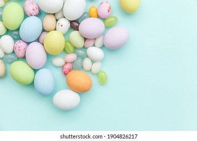 Happy Easter Concept. Preparation For Holiday. Easter Candy Chocolate Eggs And Jellybean Sweets Isolated On Trendy Pastel Blue Background. Simple Minimalism Flat Lay Top View Copy Space