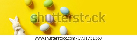 Happy Easter concept. Preparation for holiday. Easter candy chocolate eggs bunny and jellybean sweets isolated on trendy pastel blue background. Simple minimalism flat lay top view copy space banner