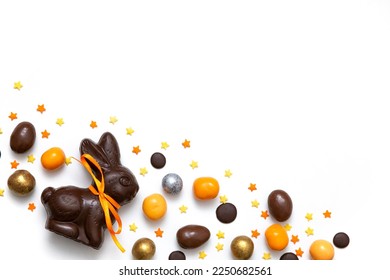 Happy Easter concept. Traditional chocolate Easter bunny, eggs, sweets, almonds, sugar stars on white table background. Preparation for holiday. Simple minimalism flat lay, top view, copy space