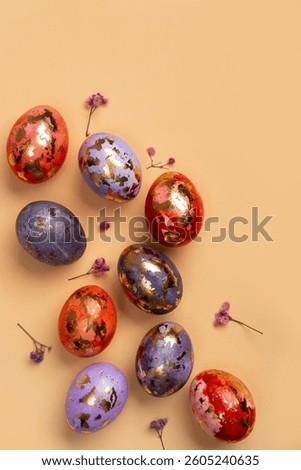 Happy Easter day! Сomposition with modern Easter eggs with gold decorations and spring flowers on beige background. Easter holiday background with stylish eggs decorations. Flat lay, copy space.