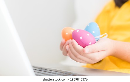 Happy Easter Day.Asian Child Girl In Rabbit Ears Holding Eggs.Online Worship In Easter Holidays With Laptop.Kid Child Online With Bunny Hat, Easter Egg Hunt Online At Home.Lockdown, Covid19, Medical.