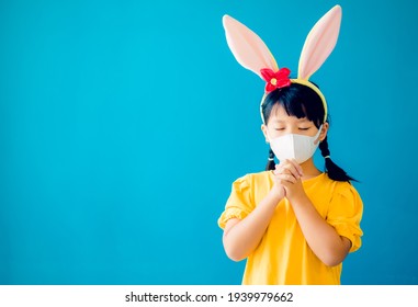 Happy Easter Day.Asian Child Girl Mask In Rabbit Ears Pray.Faith Prayer Online Worship In Easter Day Home.Kid Child Medical Mask.Healthcare, Easter Worship Home Church.Lockdown, Covid19 Coronavirus.