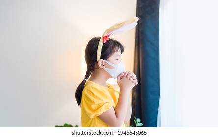 Happy Easter Day.Asian Child Girl Mask In Rabbit Ears Pray.Faith Prayer Online Worship In Easter Day Home.Kid Child Medical Mask.Healthcare, Easter Worship Home Church.Lockdown, Covid19 Coronavirus.