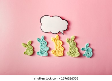 Happy Easter. Easter Decoration, Bunny Rabbits Made Of Crochet Colorful Yarn With Text Bubble On Pink Background. Homemade Decor. Top View. Spring Easter Holydays Concept, Spring Season.