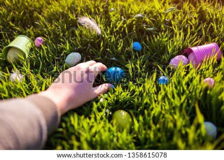 Happy Easter. Easter eggs hidden in spring grass. Woman holding egg
