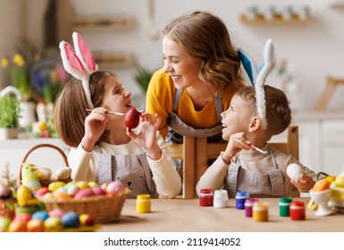Happy easter! family mother and  cheerful children  with ears are getting ready for holiday and painting eggs