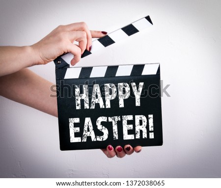 Happy Easter. Female hands holding movie clapper 