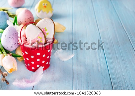 Happy Easter gingerbread cookie eggs with bucket and tulips with colorful eggs on blue wood background,
