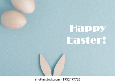 Happy Easter greeting card. On a blue background, congratulations on Easter. The rabbit's ears stick out at the bottom. There are two eggs at the top.