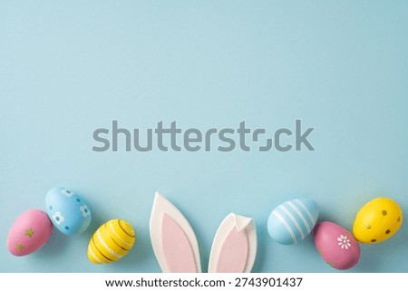 Happy Easter greeting featuring pastel decorated eggs and playful bunny ears on a soft blue background for spring celebration and holiday card design