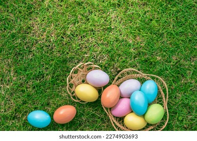 Happy Easter holiday greeting card concept. Colorful Easter Eggs and spring flowers on green grasses background. Top view, flat lay, copy space.