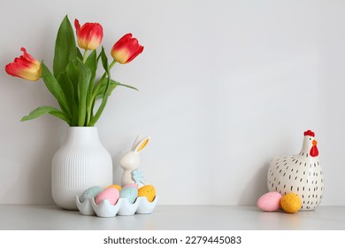 Happy Easter home decor. Table with vase of tulips, colorful Easter eggs, decorative bunny and chicken.