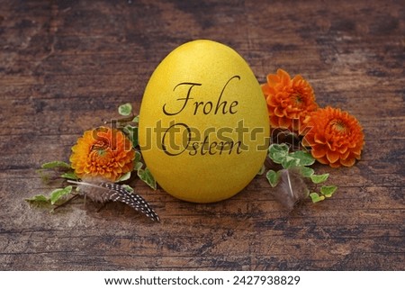 Happy Easter: Inscribed Easter egg on wooden background with flowers. German inscription reads Happy Easter.