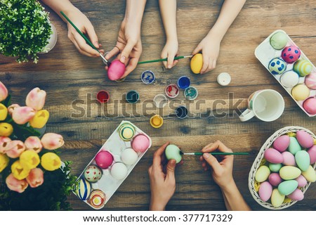 Happy easter! A mother, father and their daughter painting Easter eggs. Happy family preparing for Easter. 