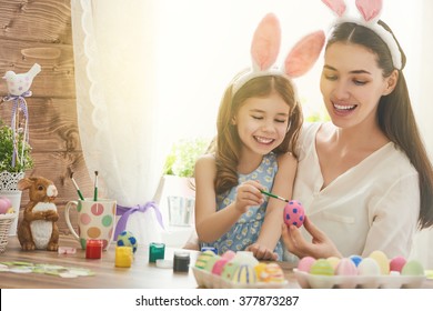 Happy easter! A mother and her daughter painting Easter eggs. Happy family preparing for Easter. Cute little child girl wearing bunny ears on Easter day. - Powered by Shutterstock