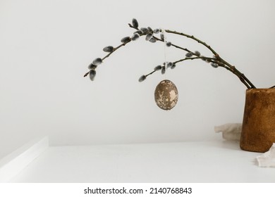 Happy Easter! Easter rustic minimalist still life. Natural easter eggs hanging on willow branches on wooden table. Simple stylish easter decoration on table aesthetics