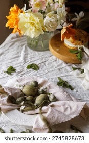 Happy Easter! Stylish eggs on napkin on plate, easter cake on stand, spring flowers. Easter celebration table setting, holiday still life. Greeting card or banner