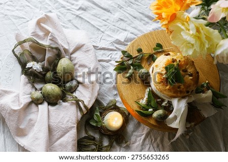 Happy Easter! Stylish eggs on napkin on plate, easter cake on stand, spring flowers and candle. Easter celebration table setting, holiday still life. Greeting card or banner