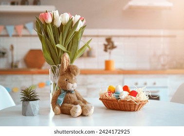 Happy Easter! Table decorating for holiday. Background with colorful eggs in basket a bouquet of tulips and a plush rabbit.