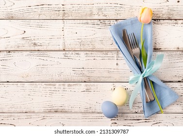 Happy Easter. Table Setting For Easter Feast. Easter Eggs, Tulips And Cutlery Top View Flat Lay On White Rustic Background