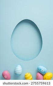 Happy Easter vertical greeting scene featuring pastel decorated eggs along the bottom of a blue paper background with a cutout egg shape for seasonal card or invitation design