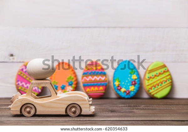 Happy easter! Wooden toy\
retro car carries eggs on a wooden background. Easter conceptual\
background.