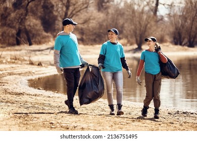 Happy eco-friendly volunteers talking while walking with garbage bags full of trash they picked up in nature.  - Powered by Shutterstock