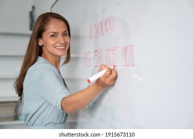 Happy educator writing instructions on white board and smiling at camera - Powered by Shutterstock