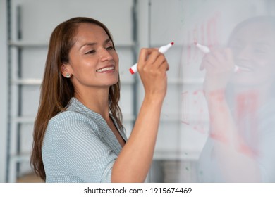 Happy educator writing with marker on the whiteboard - Powered by Shutterstock