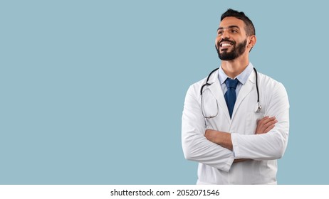 Happy Egyptian Physician Man Smiling Looking Aside Posing With Stethoscope Near Copy Space Standing In Studio Over Blue Background. Doctor's Portrait. Medical Career Concept - Powered by Shutterstock