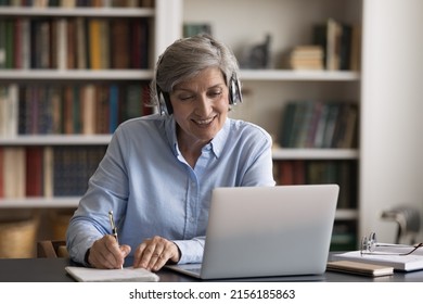 Happy Elder Student In Headphones Watching Learning Webinar On Laptop, Virtual Workshop, Writing Notes. Getting Knowledge, New Profession, Studying Online From Home, Taking E-learning Course